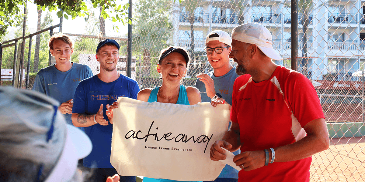 Smiling group on a tennis court holding an Active Away banner.