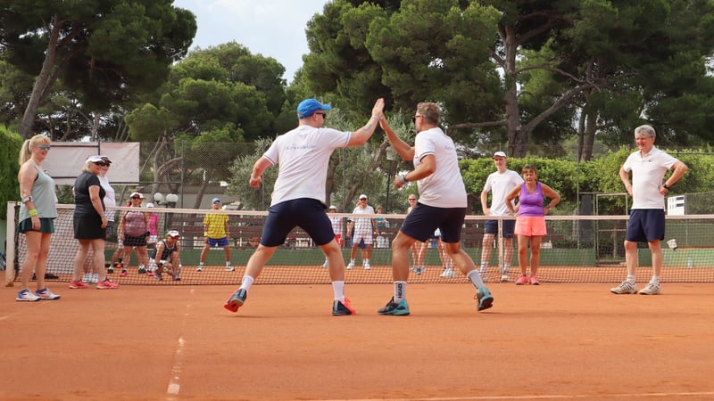 Coaches high-fiving during a group tennis session at Beach Club Mallorca