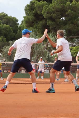 Coaches high-fiving during a group tennis session at Beach Club Mallorca