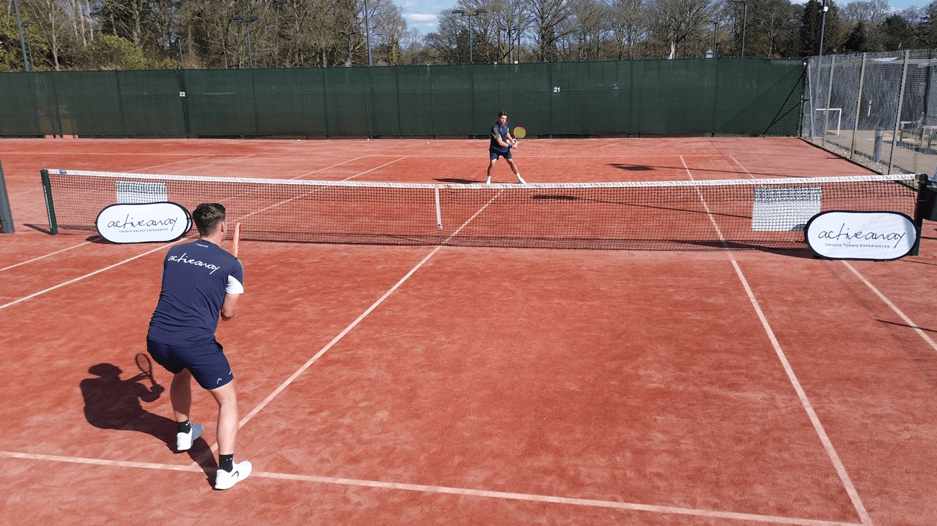Two players rally on a clay tennis court during an Active Away session.