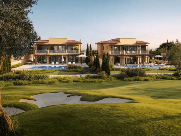 Two Mediterranean villas with pools overlooking a manicured golf course at sunset.