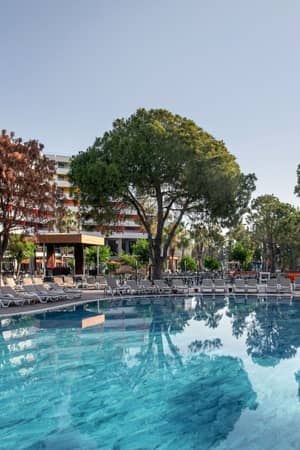 Outdoor activity pool surrounded by mature trees at Megasaray Resort Side.