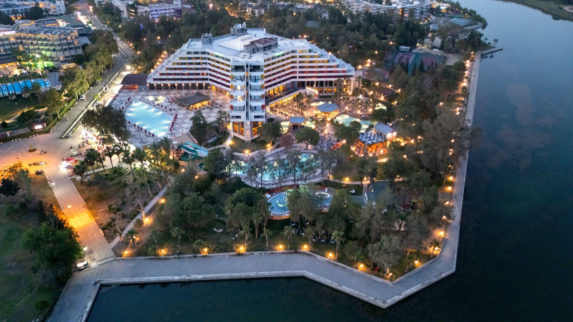 Aerial view of Megasaray Resort Side illuminated at dusk beside Titreyengöl.