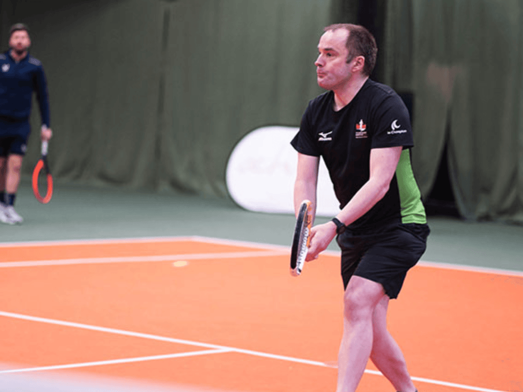 Participant preparing to serve during an indoor tennis clinic at West Bridgford.