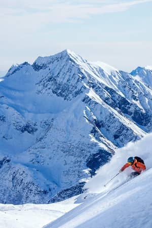 Skier descending a powder slope in the Monterosa Ski area with mountain peaks behind