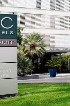 Exterior of AC Hotels by Marriott with a sign reading 'AC Victoria Suites' and landscaped entrance.