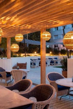 Outdoor dining area at AC Hotels with wicker furniture, marble tables, and ambient hanging lamps.