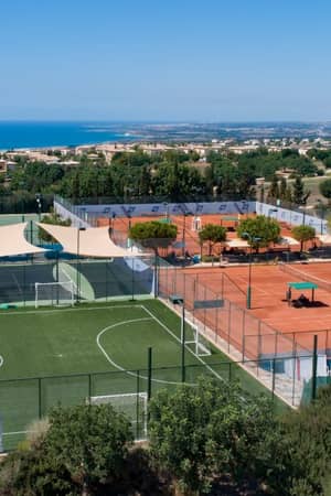 Aerial view of Aphrodite Hills sports complex featuring padel courts and football pitches with the Mediterranean Sea in the background.