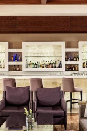 Luxurious bar at Aphrodite Hills Tennis Gallery with plush seating and shelves of premium spirits.
