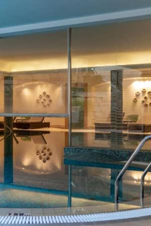 Indoor pool at Aphrodite Hills Resort with modern design, ambient lighting, and glass walls.