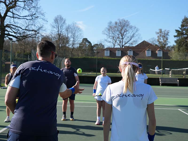 Junior tennis camp at Royal Russell School with Active Away coaches instructing children on tennis techniques on an outdoor court.