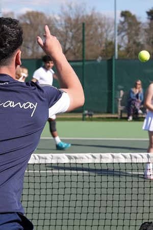 Tennis coach instructing young players on outdoor courts at Active Away Junior Tennis Camps, Royal Russell School.