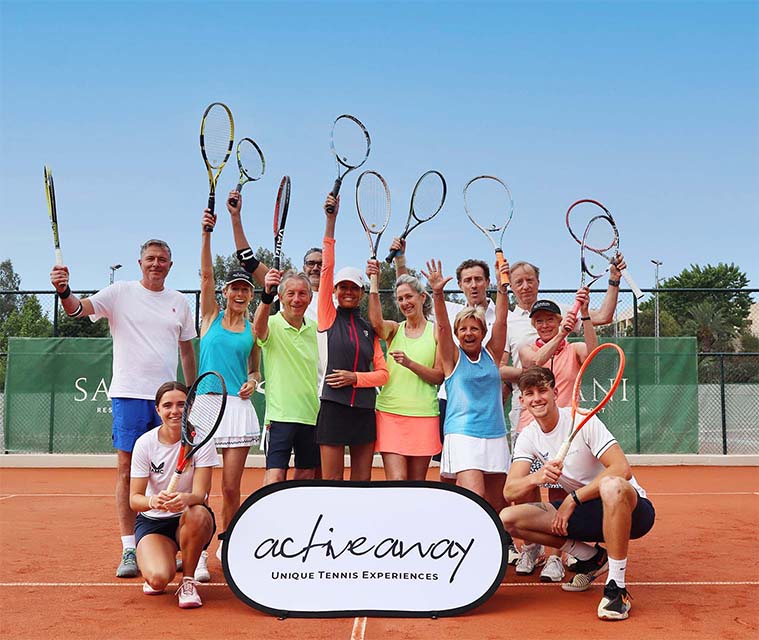 Adults posing on a clay tennis court holding racquets during an Active Away tennis holiday, with a banner reading 'Unique Tennis Experiences'.