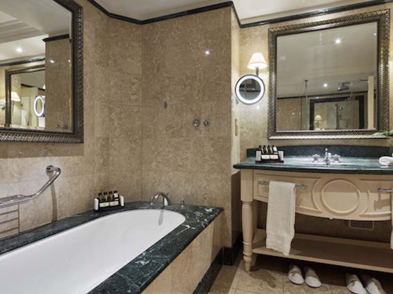 Luxury bathroom at Aphrodite Hills with marble bathtub, ornate mirror, and vanity.