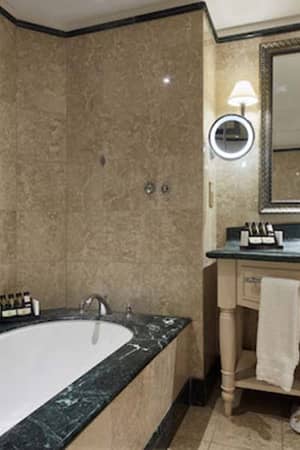 Luxury bathroom at Aphrodite Hills with marble bathtub, ornate mirror, and vanity.