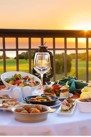 Gourmet dining setup with appetisers and wine on a table overlooking a sunset at Aphrodite Hills Resort.