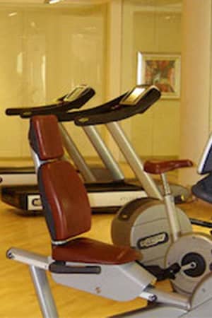 Interior of Aphrodite Hills Gym featuring treadmills and stationary bikes on a wooden floor with soft lighting.