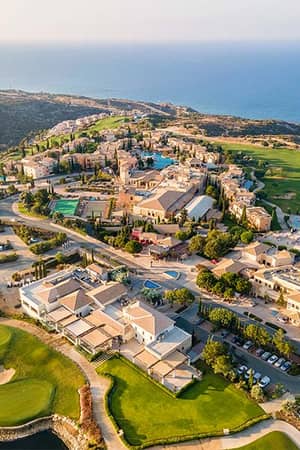 Aerial view of Aphrodite Hills Resort in Cyprus with golf course and Mediterranean Sea in the background.