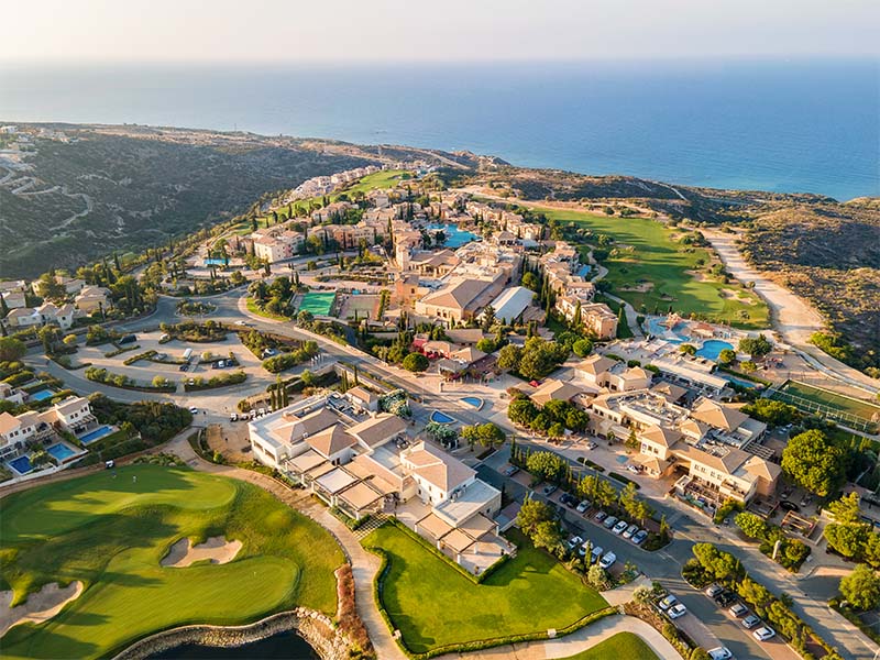 Aerial view of Aphrodite Hills Resort in Cyprus with villas, golf courses, and the Mediterranean Sea.
