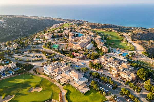 Aerial view of Aphrodite Hills Resort in Cyprus with villas, golf courses, and the Mediterranean Sea.