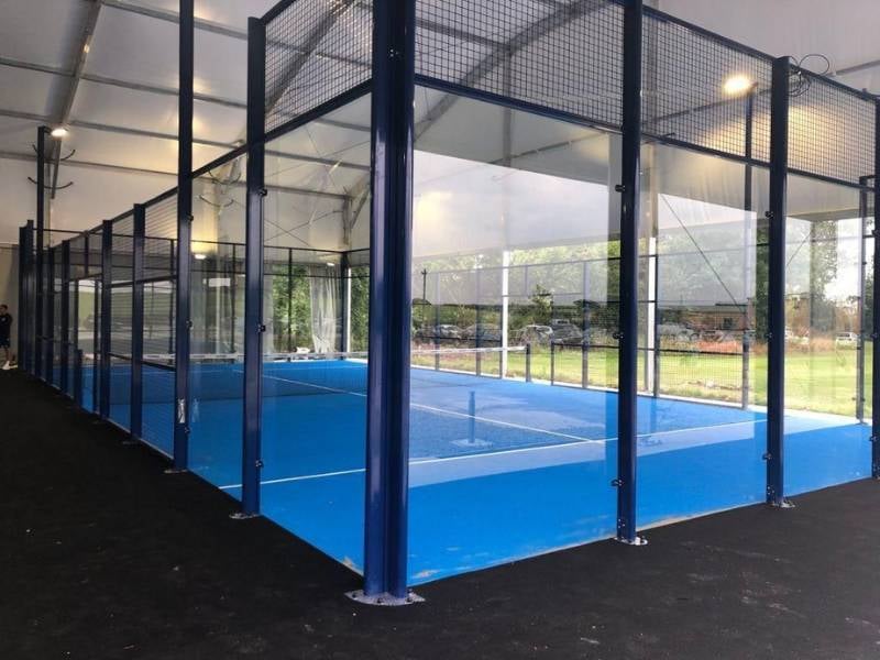 Professional padel court with blue metal fencing and playing surface under a roof, at BD Swindon Gallery.