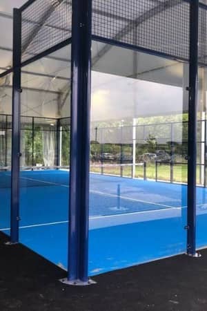 Professional padel court with blue metal fencing and playing surface under a roof, at BD Swindon Gallery.