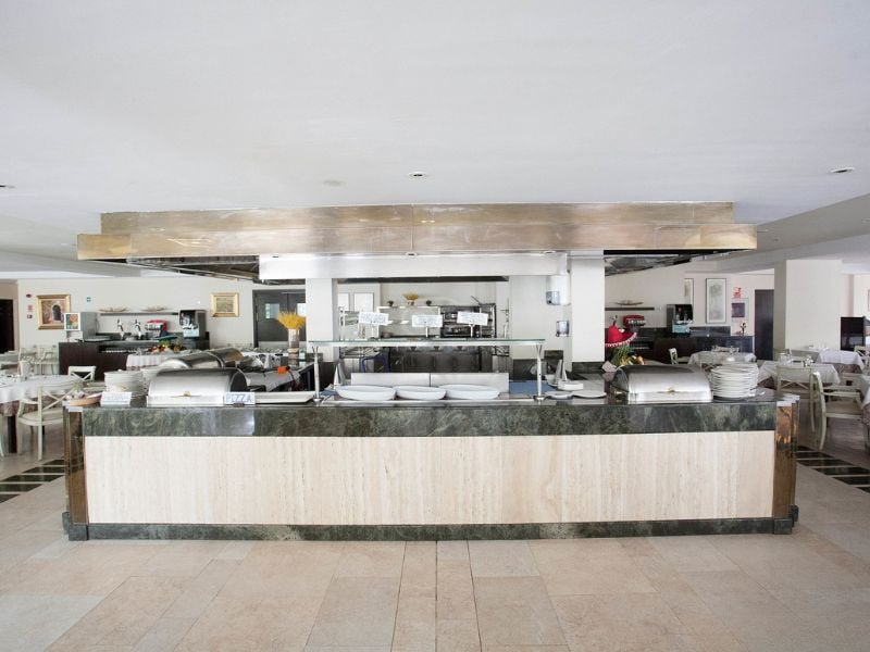 Buffet area in a beach club with a marble counter, stainless steel hood, and well-organised kitchen in the background.