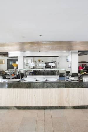 Buffet area in a beach club with a marble counter, stainless steel hood, and well-organised kitchen in the background.