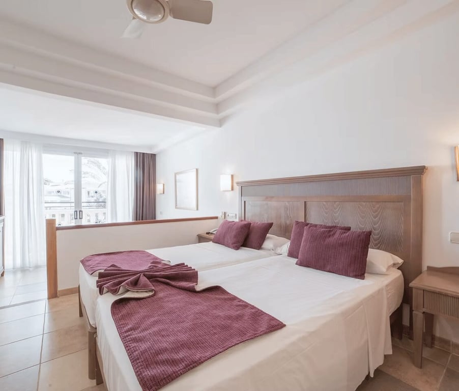 Beach Club Junior Suite with a double bed, purple cushions, ceiling fan, and balcony with natural light.