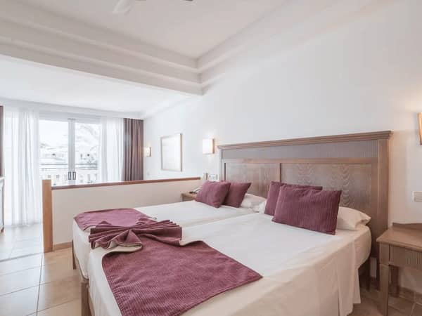 Beach Club Junior Suite with a double bed, purple cushions, ceiling fan, and balcony with natural light.