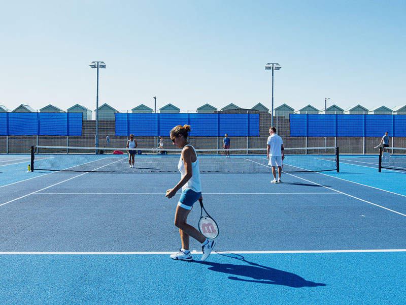 Players on a blue padel court at Brighton Tennis Padel, engaging in a doubles match on a sunny day.