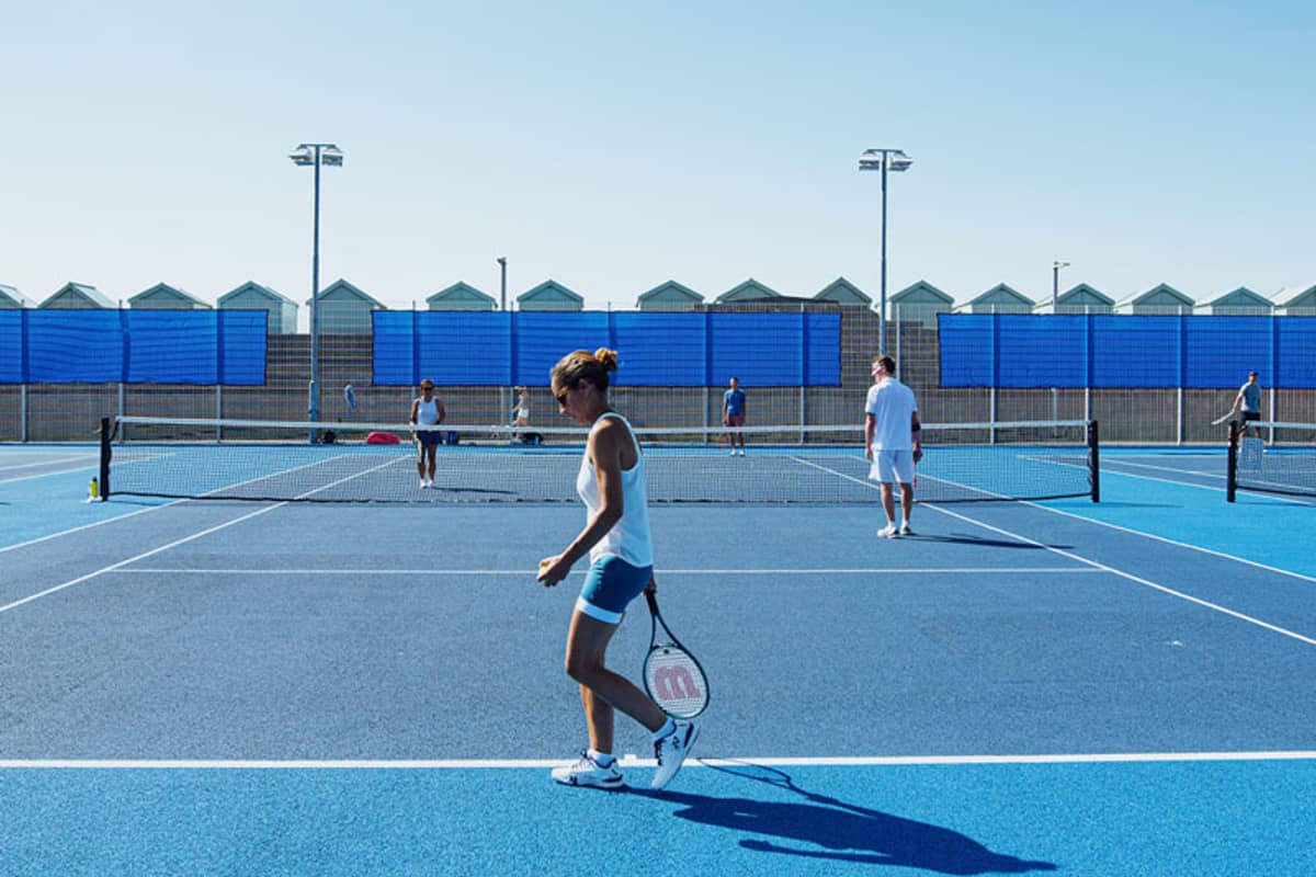 Players on a blue padel court at Brighton Tennis Padel, engaging in a doubles match on a sunny day.
