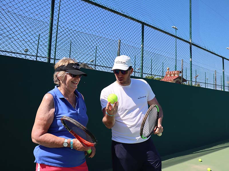 Tennis coach instructing a female player during the Brighton Tennis and Padel Weekend on an outdoor court.