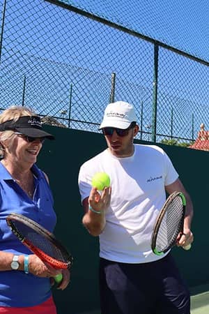 Tennis coach instructing a female player during the Brighton Tennis and Padel Weekend on an outdoor court.