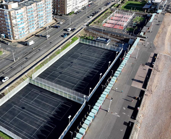 Aerial view of Brighton's tennis and padel courts near the beach and city buildings.