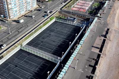 Aerial view of Brighton's tennis and padel courts near the beach and city buildings.