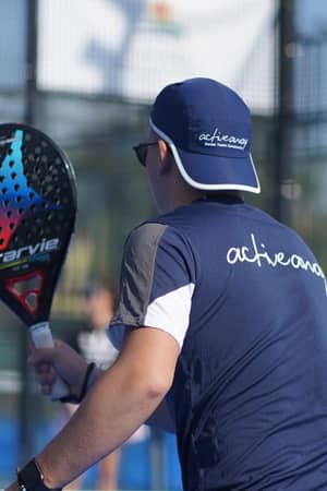 Padel coach holding a StarVie racket on an outdoor court with a blue activewear uniform.