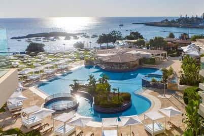 Luxurious seaside resort at Capo Bay with an outdoor pool, sun loungers, and a view of the bay.