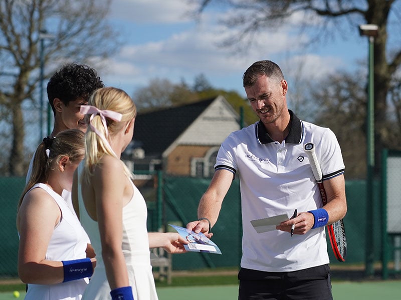 Jamie Murray hands out leaflets to junior tennis students at Churcher's School tennis courts.