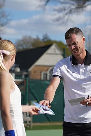 Jamie Murray hands out leaflets to junior tennis students at Churcher's School tennis courts.