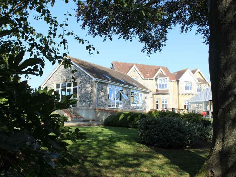 Outdoor view of Churcher's School student dormitories with traditional stone and brick architecture surrounded by greenery.