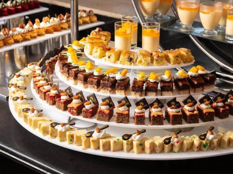Assorted pastries and cakes on tiered circular trays at Cleopatra Gallery's dessert selection.