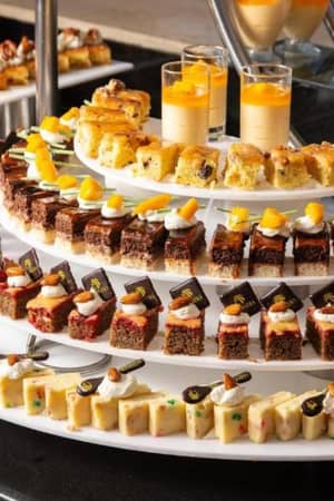 Assorted pastries and cakes on tiered circular trays at Cleopatra Gallery's dessert selection.