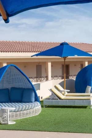 Outdoor lounge with canopy sofas and blue umbrellas on faux grass at Cleopatra Gallery.