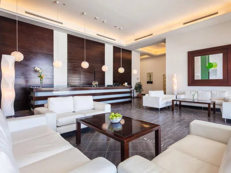 Luxurious hotel lobby at Cleopatra Gallery with white leather sofas, wooden panelling, and modern light fixtures.
