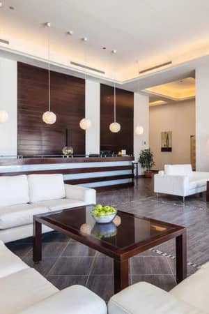 Luxurious hotel lobby at Cleopatra Gallery with white leather sofas, wooden panelling, and modern light fixtures.