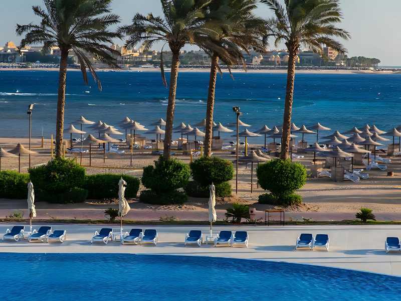 Outdoor pool and loungers at Cleopatra Luxury Resort with beach and sea view in the background.