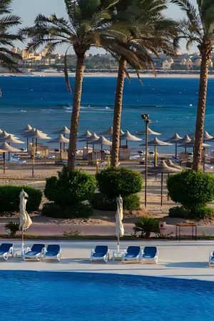 Outdoor pool and loungers at Cleopatra Luxury Resort with beach and sea view in the background.