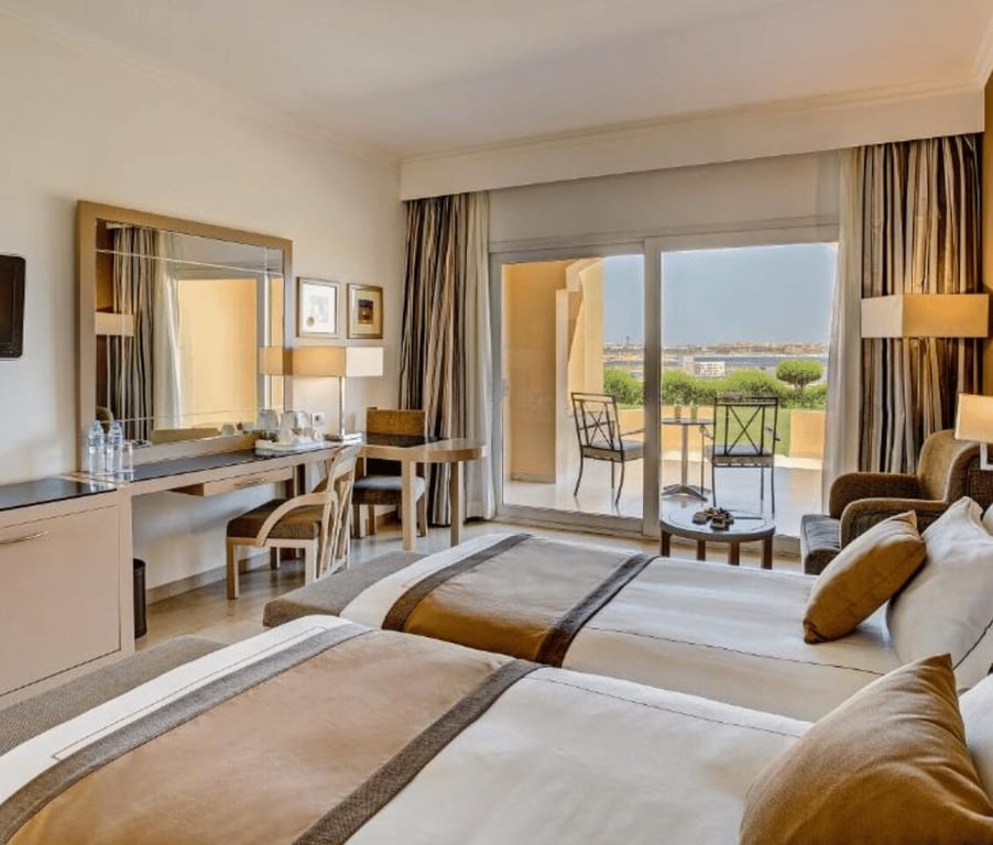 Deluxe room with twin beds in Cleopatra Luxury Resort, featuring a desk, seating area, and balcony with beach view.