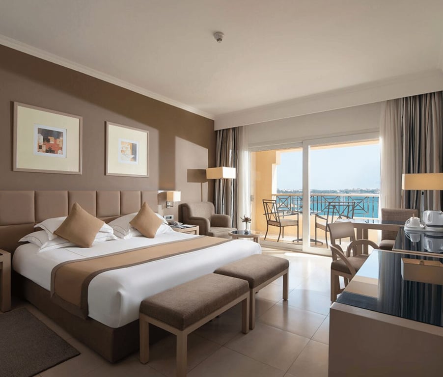 Luxurious Cleopatra Premium Deluxe Room with a king-sized bed, modern seating area, and private balcony overlooking the sea.